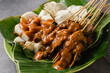 sate padang, indonesian cuisine padang beef, intestine satay with spicy peanut sauce and rice cake,