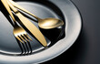 © m________k____ - Gold knives, forks and spoons on black plates.
