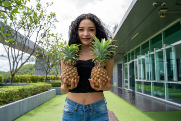 Happy young woman showing pineapple. Pineapple fruit woman smiling healthy and joyful. Mixed-race Asian / Caucasian model with pineapple