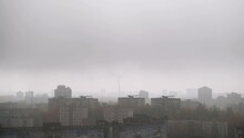 White Smog Over Roofs Of Buildings, Crow Flies In Foggy City.