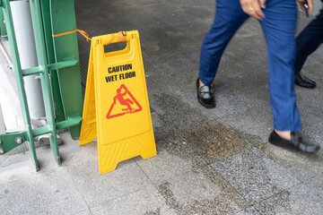 Yellow Caution slippery wet floor sign on the wet ground