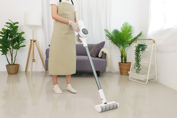 Lifestyle in living room concept, Young Asian woman using vacuum cleaner to cleaning the floor