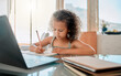© Kirsten D/peopleimages.com - Zoom class, home school lesson and online education with little kid writing homework and test for distance learning on video call laptop. Child, young girl and student studying with virtual teaching