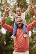 A Young Black Father Playing With His Daughter Happy, Smiling And Bonding While Enjoying Quality Time Together. A Little Girl, Child Or Kid Having Fun And Sitting On Her Dad Or Parents Shoulders