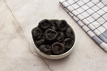 Wall Mural - Dried plums in a white bowl isolated on marble background