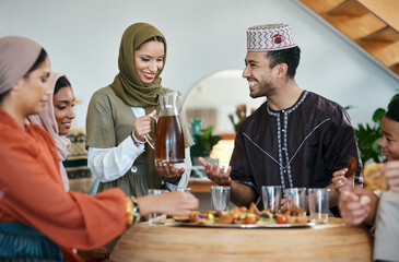 Poster - Group of muslim people celebrating Eid or Ramadan with iftar at home with food, drink and family. Young Islam woman pouring juice for a happy, smiling and positive man while breaking fast together