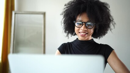 Wall Mural - A young woman with glasses is working using a laptop in the office typing text