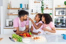 Overjoyed Young Family With Daughter Have Fun Cooking Baking Pastry Or Pie At Home Together, Happy Smiling Parents Enjoy Weekend Play With Child Doing Bakery Cooking In Kitchen