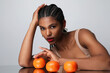 © face_reader_img - African American woman with long dark braids and orange fruits poses indoor.