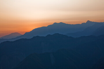 Wall Mural - Sunrise view of magnificent layered mountains with colorful clouds background