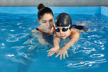 Wall Mural - Little boy learning to swim in pool with teacher