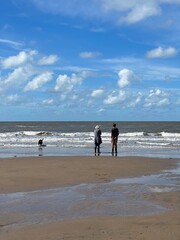 Canvas Print - Couple walking there dog on the beach with waves crashing onto the beach. Taken in Fleetwood Lancashire England. 