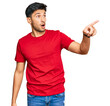 © Krakenimages.com - Young handsome man wearing casual red tshirt pointing with finger surprised ahead, open mouth amazed expression, something on the front