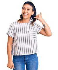 Poster - Young woman wearing casual clothes smiling doing phone gesture with hand and fingers like talking on the telephone. communicating concepts.