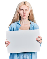 Canvas Print - Young caucasian woman holding blank empty banner making fish face with mouth and squinting eyes, crazy and comical.