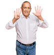 © Krakenimages.com - Handsome senior man wearing elegant white shirt showing and pointing up with fingers number nine while smiling confident and happy.