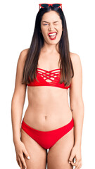 Poster - Young beautiful caucasian woman wearing bikini winking looking at the camera with sexy expression, cheerful and happy face.