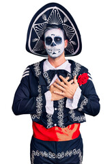 Wall Mural - Young man wearing day of the dead costume over background smiling with hands on chest with closed eyes and grateful gesture on face. health concept.