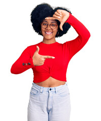 Sticker - Young african american girl wearing casual clothes and glasses smiling making frame with hands and fingers with happy face. creativity and photography concept.