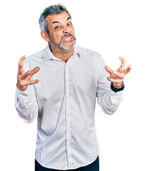 Canvas Print - Middle age hispanic with grey hair wearing casual white shirt shouting frustrated with rage, hands trying to strangle, yelling mad