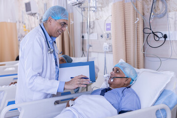 Doctor examining senior patient in critical health conditions using a stethoscope in the intensive care unit
