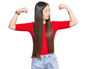 Poster - Young chinese woman wearing casual clothes showing arms muscles smiling proud. fitness concept.