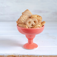 Wall Mural - Butter cookies in orange vase on white wooden background.