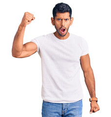 Sticker - Young latin man wearing casual clothes angry and mad raising fist frustrated and furious while shouting with anger. rage and aggressive concept.