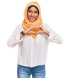 © Krakenimages.com - Young brunette woman wearing traditional islamic hijab scarf smiling in love showing heart symbol and shape with hands. romantic concept.