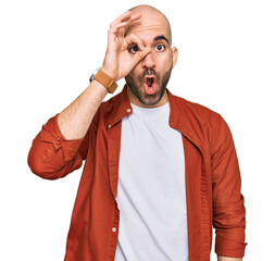 Wall Mural - Young hispanic man wearing casual clothes doing ok gesture shocked with surprised face, eye looking through fingers. unbelieving expression.