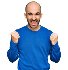 Canvas Print - Young hispanic man wearing casual clothes celebrating surprised and amazed for success with arms raised and open eyes. winner concept.