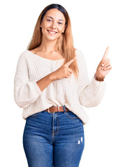 Wall Mural - Beautiful young woman wearing casual clothes smiling and looking at the camera pointing with two hands and fingers to the side.