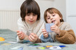 © Anna - Two brothers playing development smart game at home. Siblings spending time together, resolving logical toy.