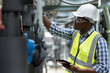 © amorn - Male plumber engineer working at sewer pipes area at construction site. African American male engineer worker check or maintenance sewer pipe network system at construction sit