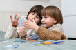© Anna - Two brothers playing development smart game at home. Siblings spending time together, resolving logical toy.