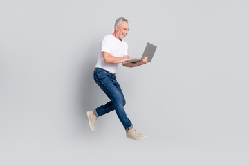 Sticker - Full length body size view of handsome cheerful man jumping using laptop typing email isolated over grey pastel color background