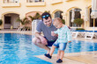 © Anna - Father and toddler child spending time near the swimming pool in luxury hotel in Egypt. Evening time in summer resort.