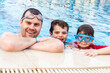 © Anna - Father with two sons spending time in a swimming pool in a hotel in summer. Dad with children spending time together.