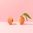 © Boba - Fresh ripe organic peach with pit and leaves cut in half against bright peach pink background. Minimal fruit concept. Healthy juicy food trendy composition.