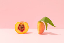 Fresh Peach Slices With Pit And Leaves Against Bright Peach Pink Background. Healthy Organic Ripe Fruits Authentic Composition.  Artistic Food Party Concept. Trendy Healthy Eathing Aesthetic.