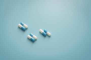 Wall Mural - Pairs of white-blue antibiotic capsule pills on blue background. Antibiotic drug. Prescription drug. Pharmacology and recommended dose concept. Pharmaceutical industry. Medical and healthcare concept.