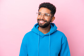 Wall Mural - Young Brazilian man isolated on pink background With glasses with happy expression