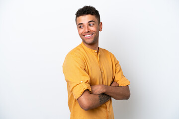 Young caucasian Brazilian man isolated on white background with arms crossed and happy