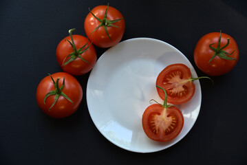 Wall Mural - Ripe beautiful tomato fruit on a white plate top view. Delicious tomatoes still life.