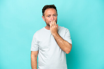 Middle age caucasian man isolated on blue background covering mouth with hand