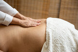 Fototapeta  - Um profissional fazendo massagem terapêutica nas costas do paciente que está deitado na maca.