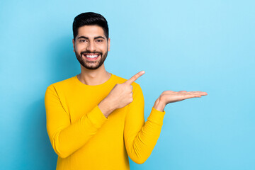 Wall Mural - Photo of cute cheerful guy dressed yellow pullover pointing holding arm empty space isolated blue color background