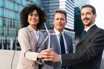 Wall Mural - Business people meeting in a business park - International business team and engineer managers holding a wind turbine, concepts about future green and clean sustainable energy