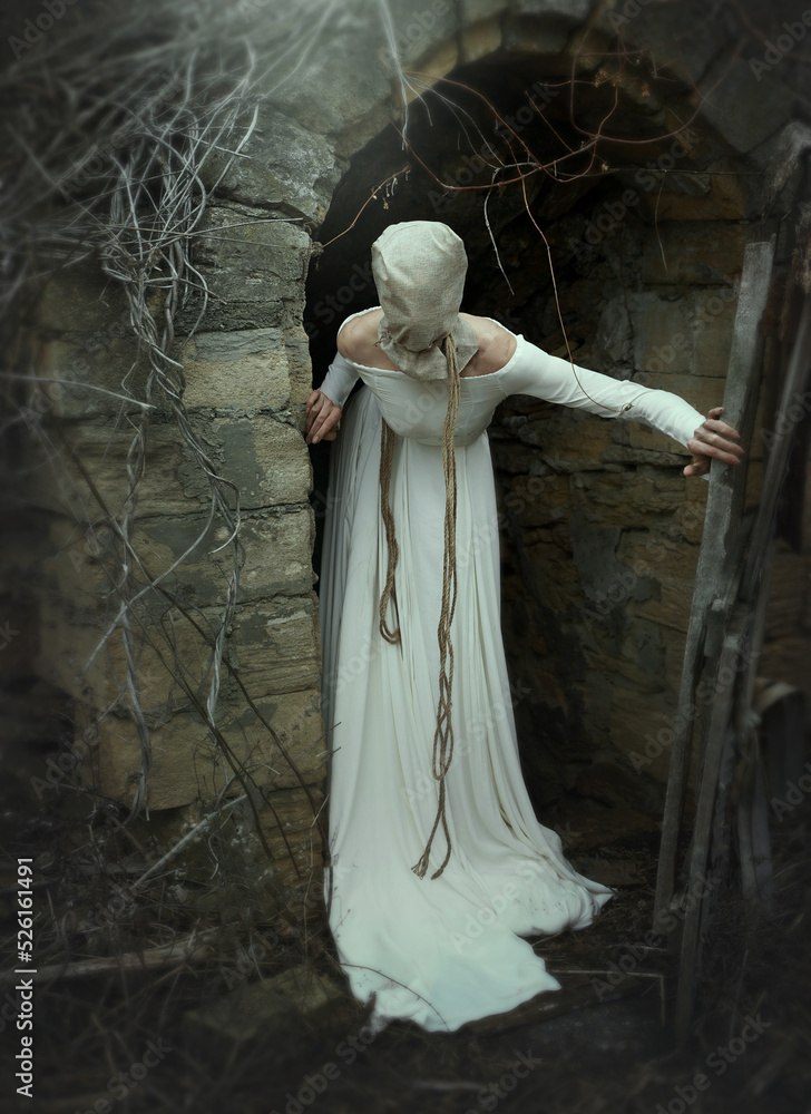 A creepy woman in a white dress with a canvas bag on her head stands at the entrance to the basement. Vintage style. Fairy tales for Halloween. Horror, thriller. Stock Photo | A creepy woman in a white dress with a canvas bag on her head stands at the entrance to the basement. Vintage style. Fairy tales for Halloween. Horror, thriller. Stock Photo |