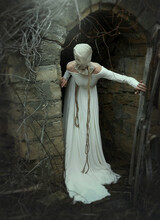 A Creepy Woman In A White Dress With A Canvas Bag On Her Head Stands At The Entrance To The Basement. Vintage Style. Fairy Tales For Halloween. Horror, Thriller.